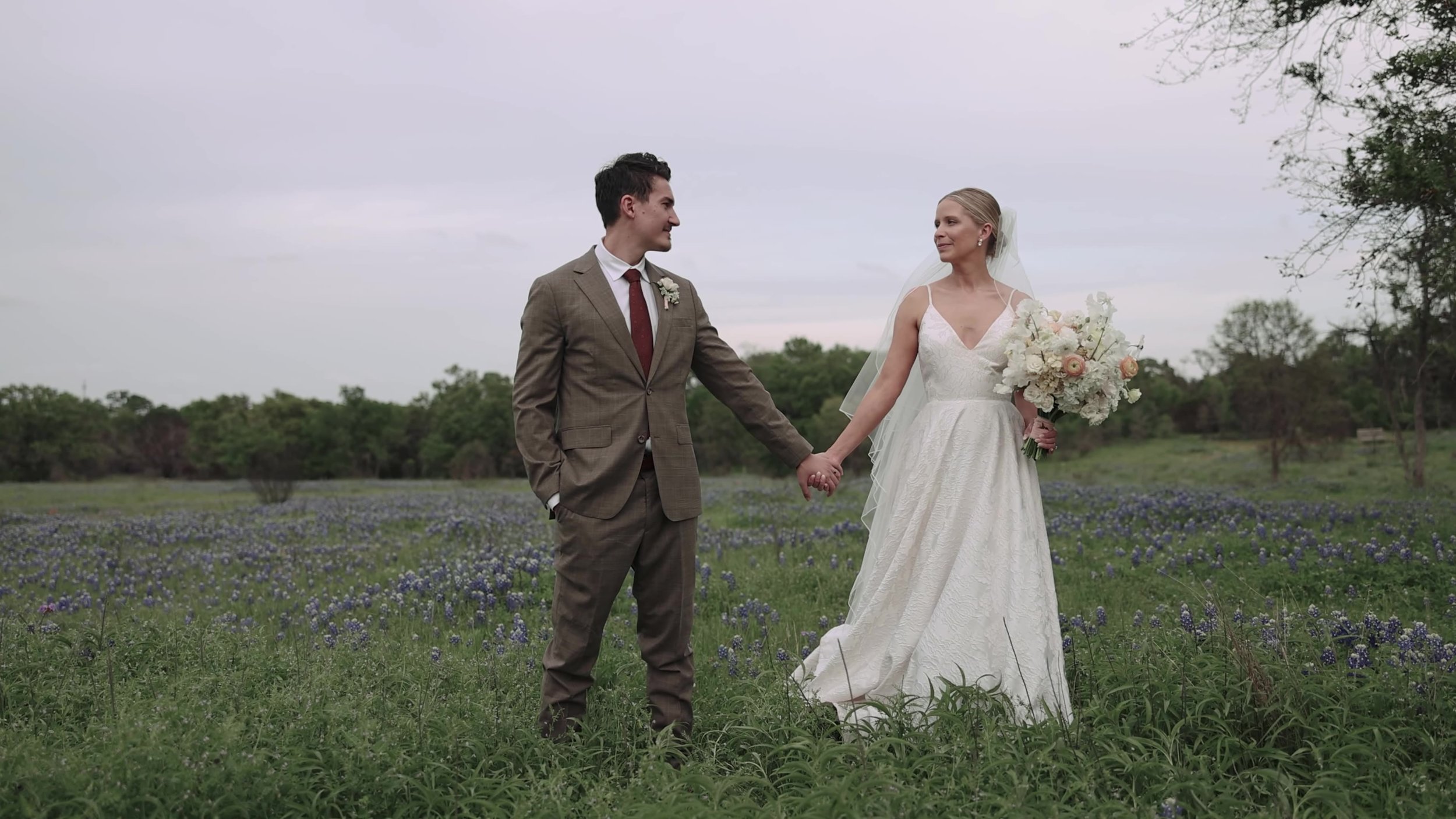 Heather and Chris holding hands in a bluebonnet field at Lady Bird Johnson Wildflower Center in Austin, Texas