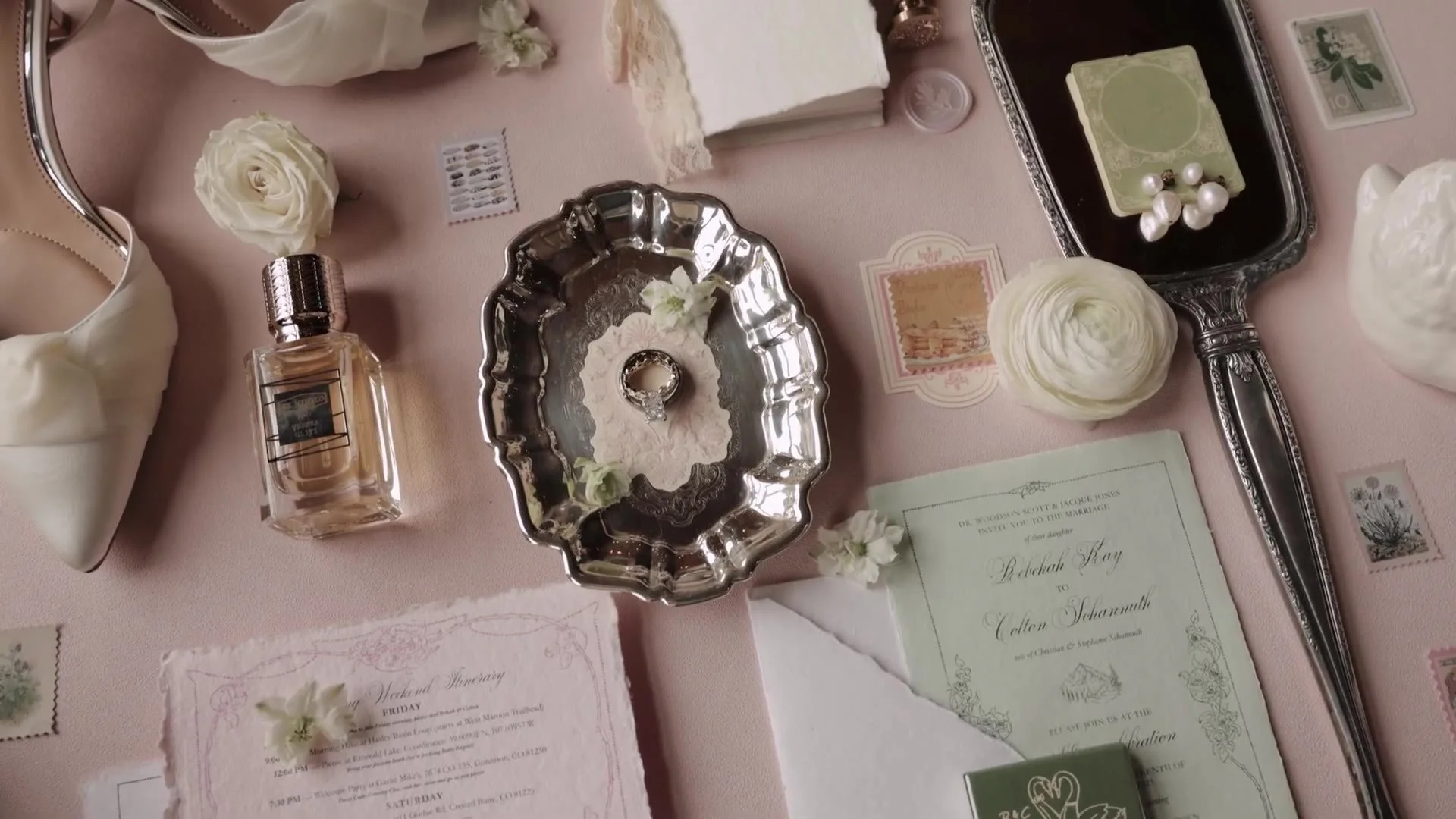 Crested Butte Wedding Garden invitation, rings on a silver tray, perfume, and a white heel on pink linen