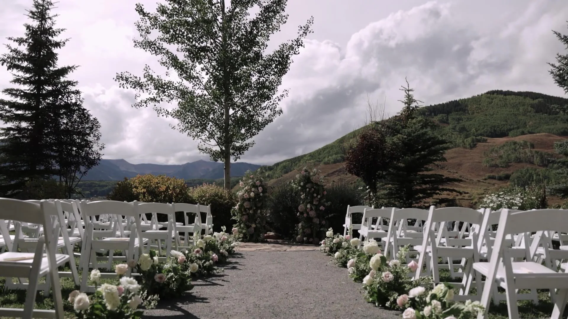 Empty ceremony aisle at Crested Butte Wedding Garden with white chairs, aisle florals, and Colorado mountains