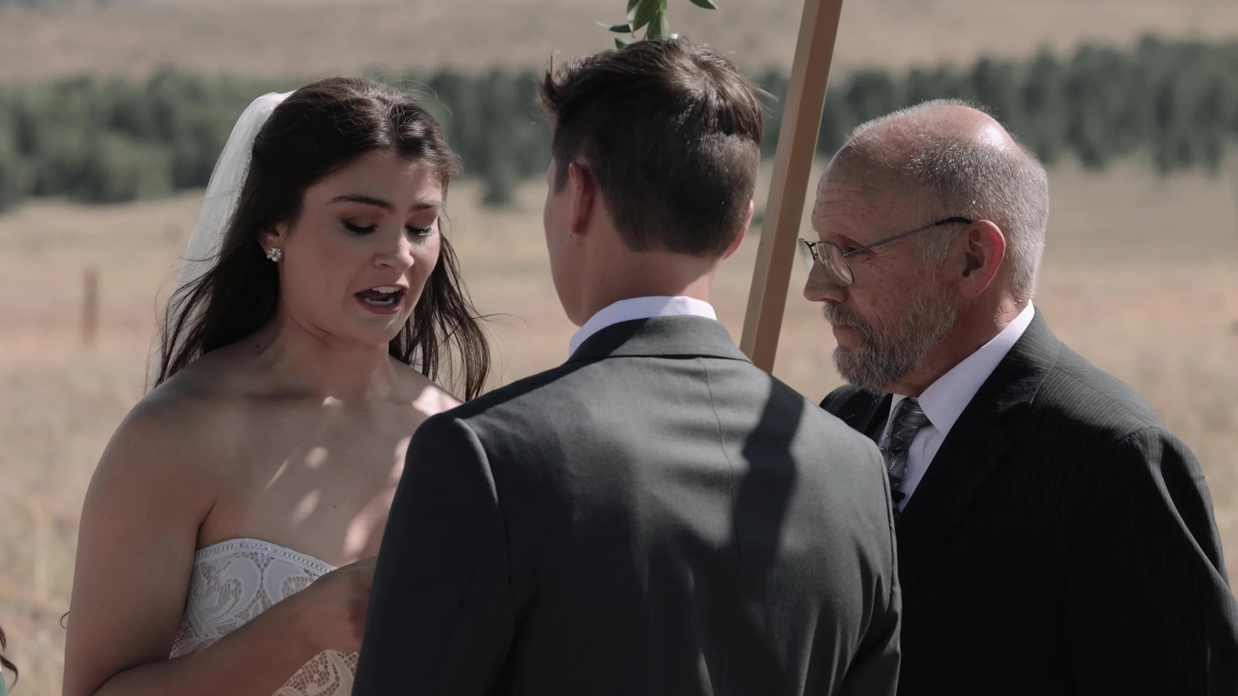 Seth and Cass exchanging vows under a wooden arch at 3 Peaks Ranch in Westcliffe, Colorado