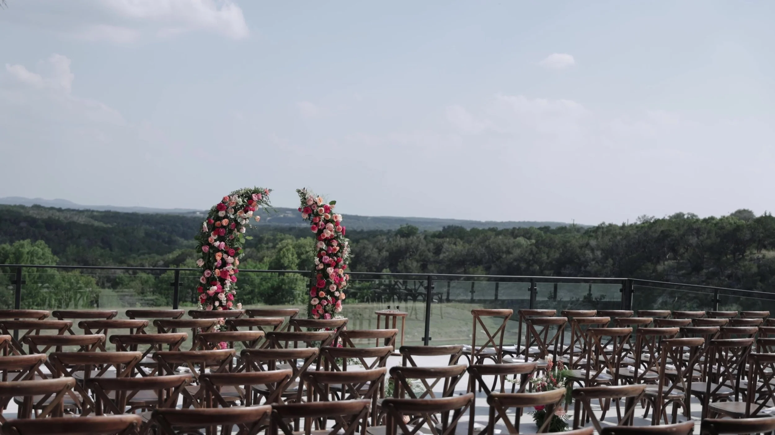 Rows of wooden chairs leading to a circular floral ceremony arch at Videre Estate Austin Texas Hill Country