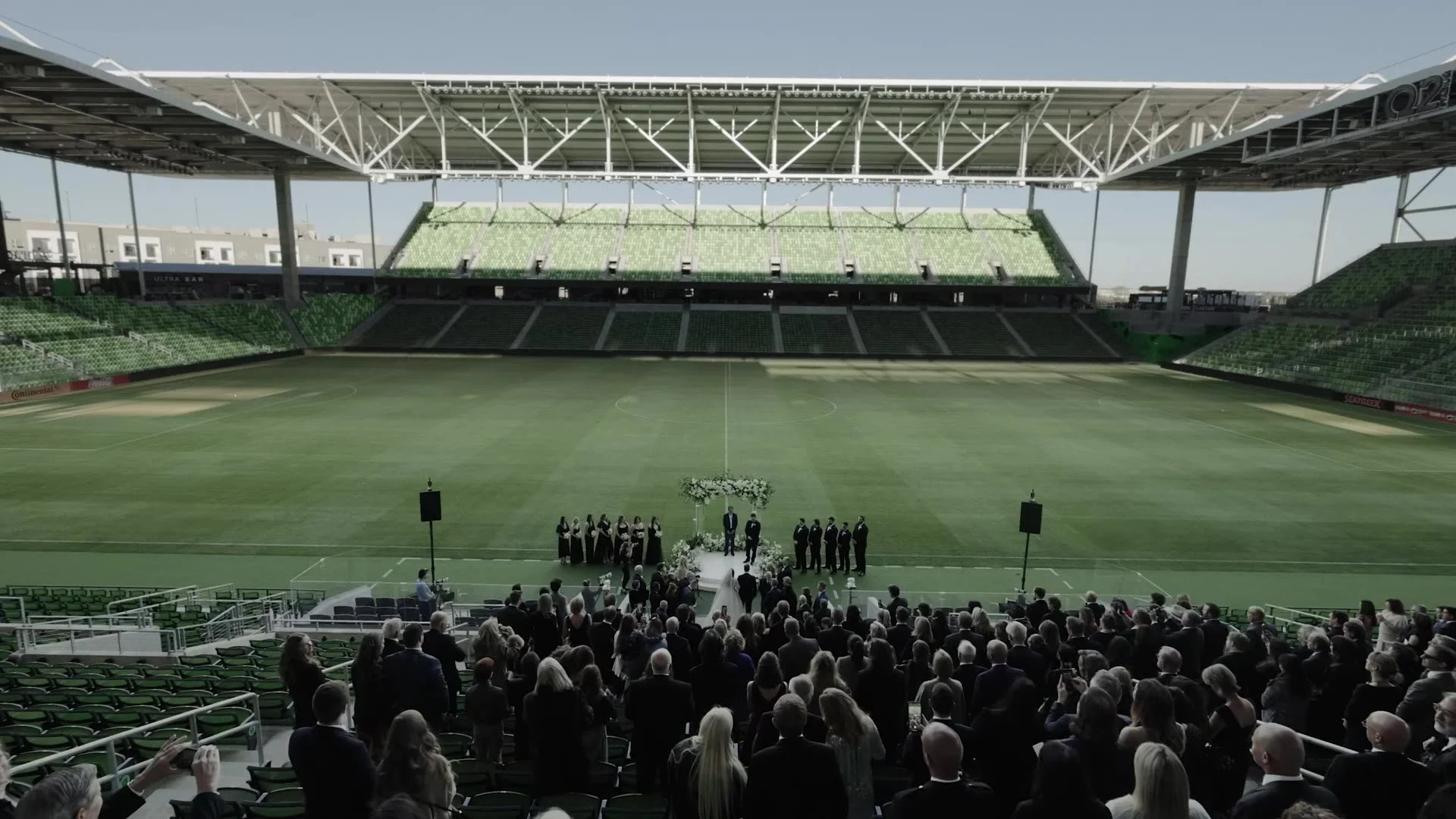 Wide view of Gabby and Nic's ceremony on the pitch with guests in the stands at Q2 Stadium Austin