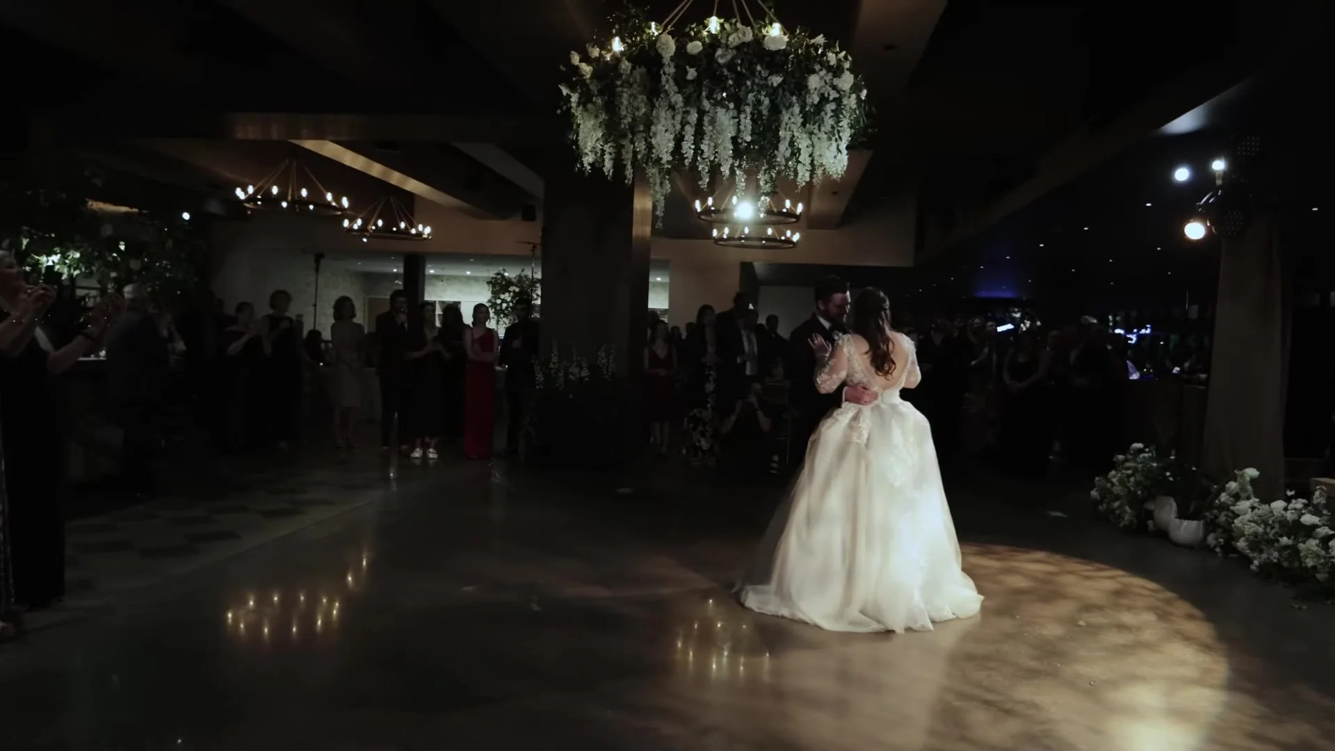 Gabby and Nic first dance under a floral chandelier at their Q2 Stadium reception in Austin, Texas