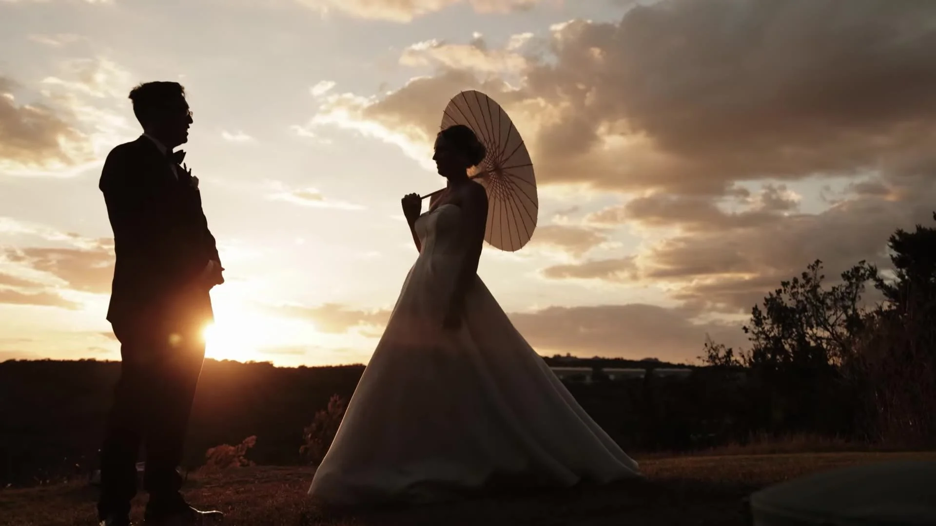 Wide sunset silhouette of Jason and Rachel facing each other at Canyonwood Ridge in Dripping Springs, Texas