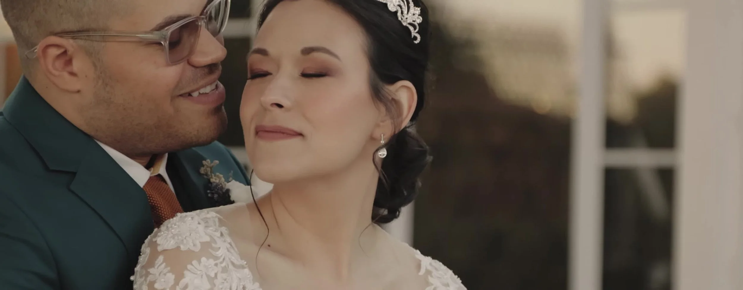 Tight shot of the couple forehead to forehead, bride in a tiara, groom in glasses and a gold tie