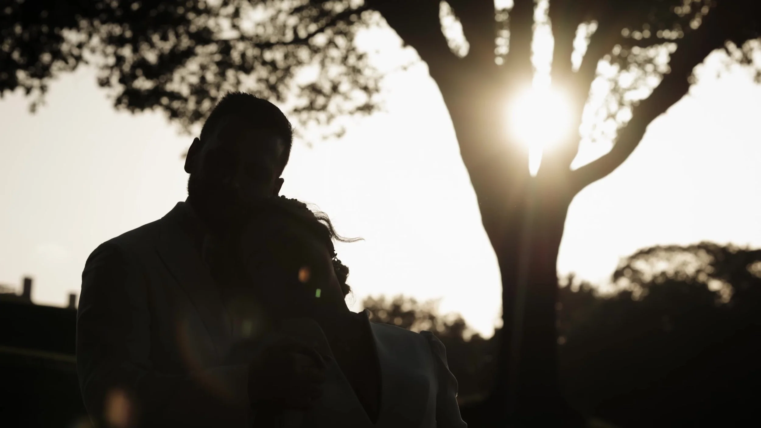 Silhouette of Keely and Jay under trees at sunset at Barton Creek Country Club in Austin