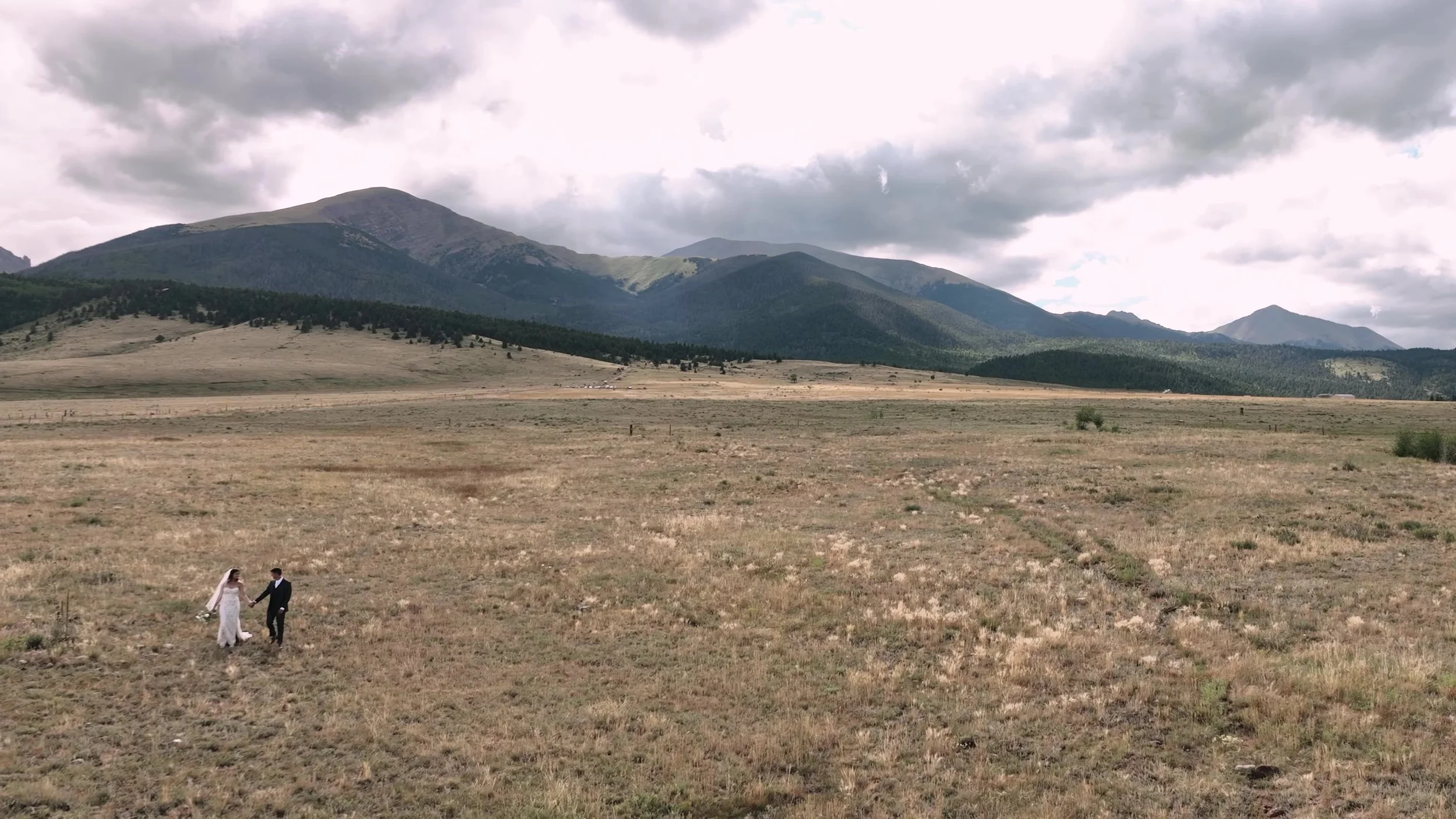 Super 8 frame of the couple walking a vast meadow at 3 Peaks Ranch in Westcliffe, Colorado
