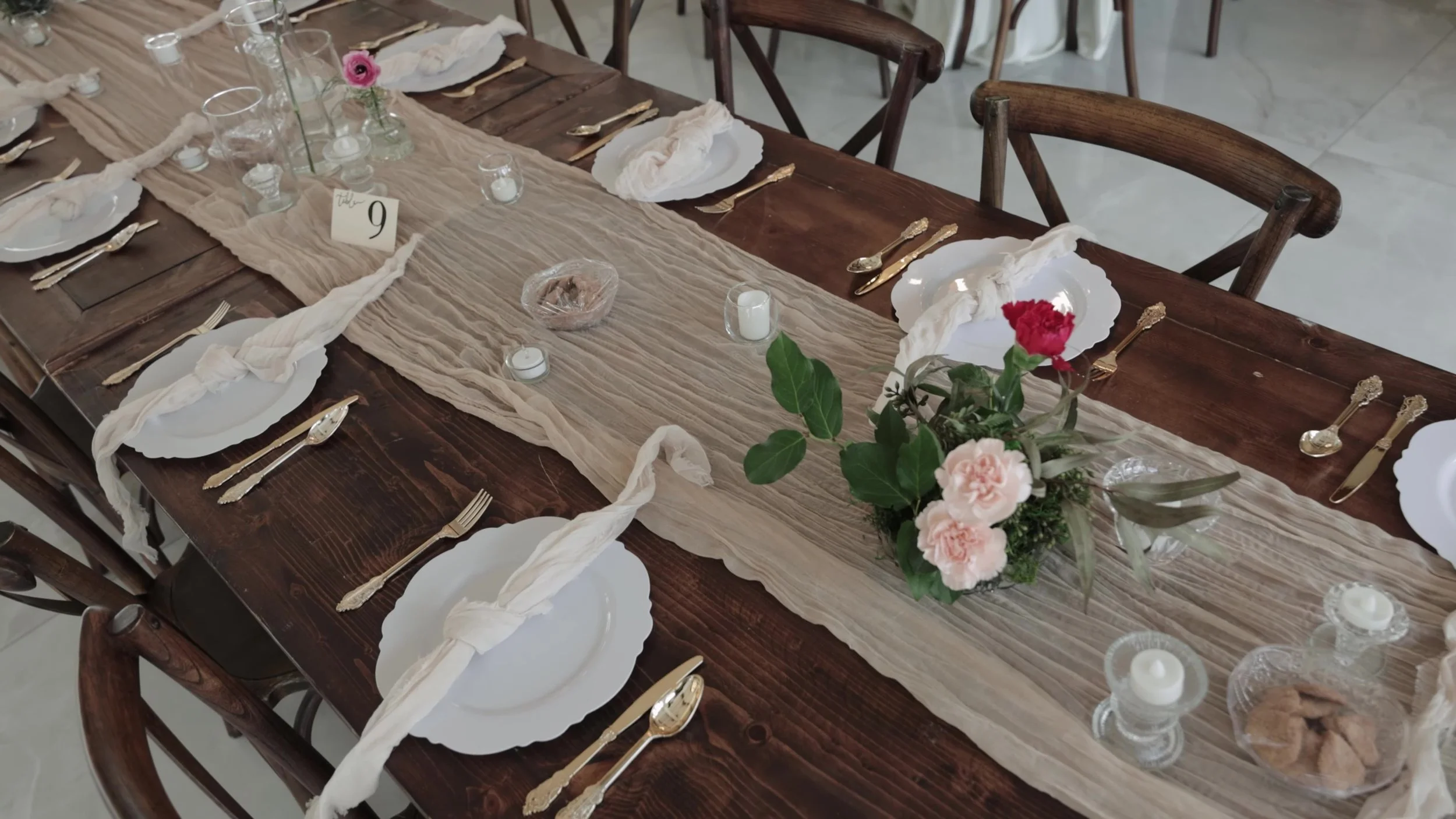 Wooden reception table with gold flatware and pink rose centerpiece at Videre Estate Austin