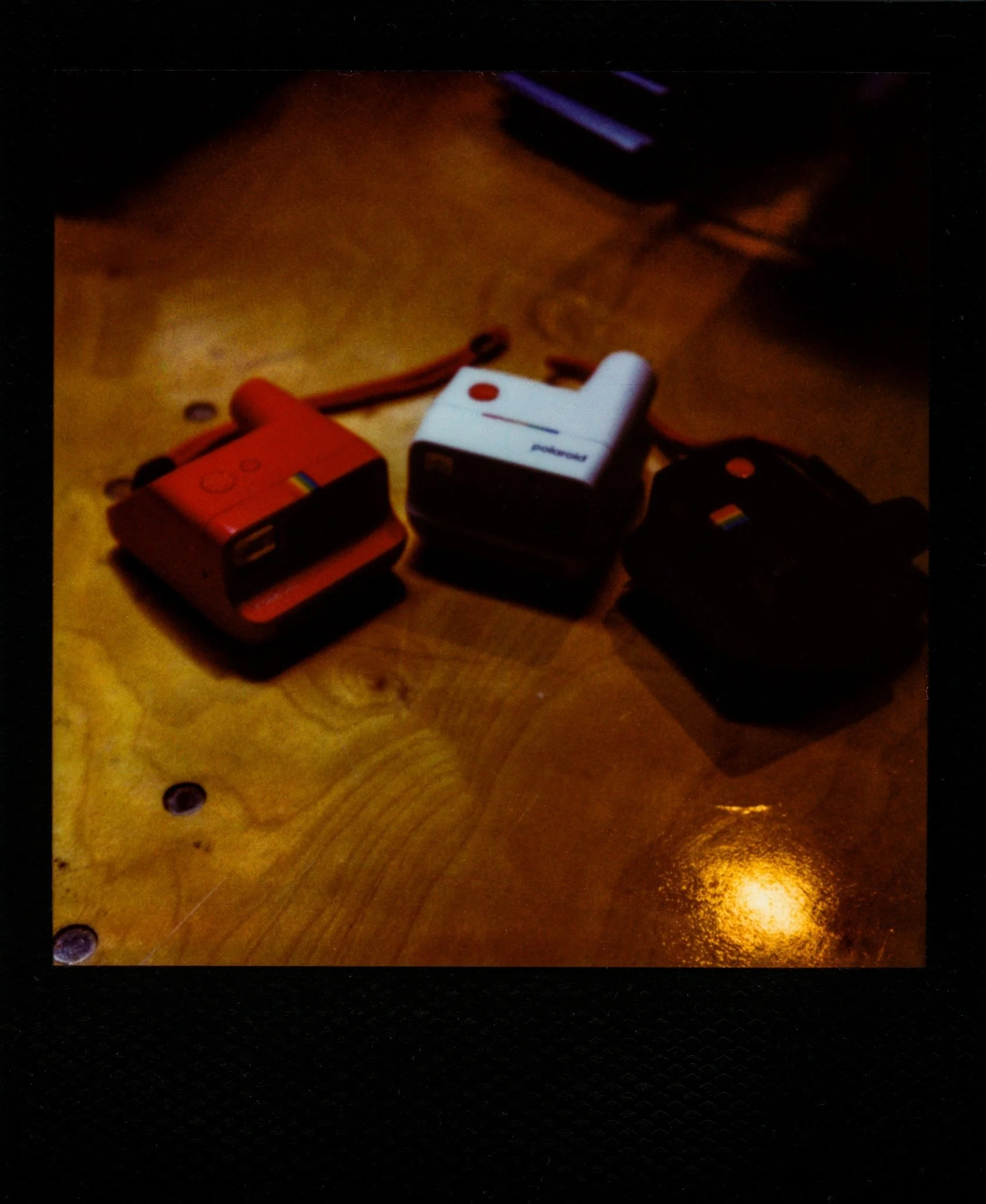 Three instant cameras on a warm table