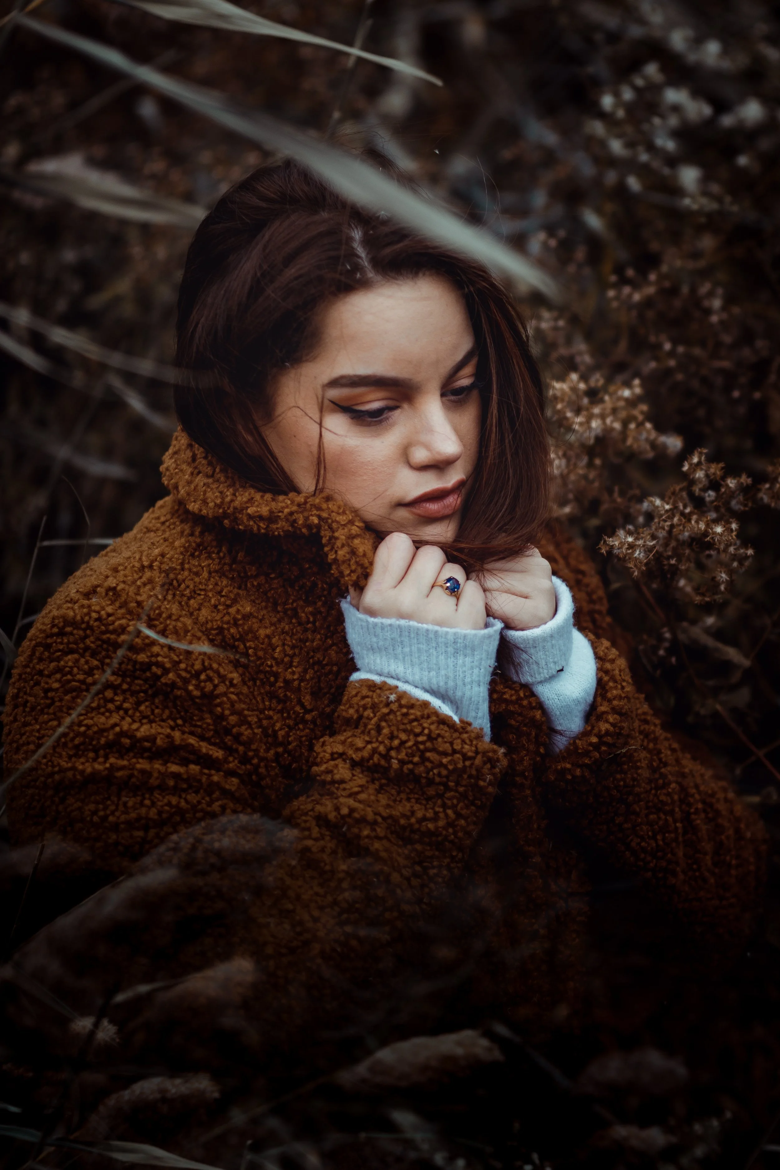Close portrait with warm coat and soft expression in fall foliage.