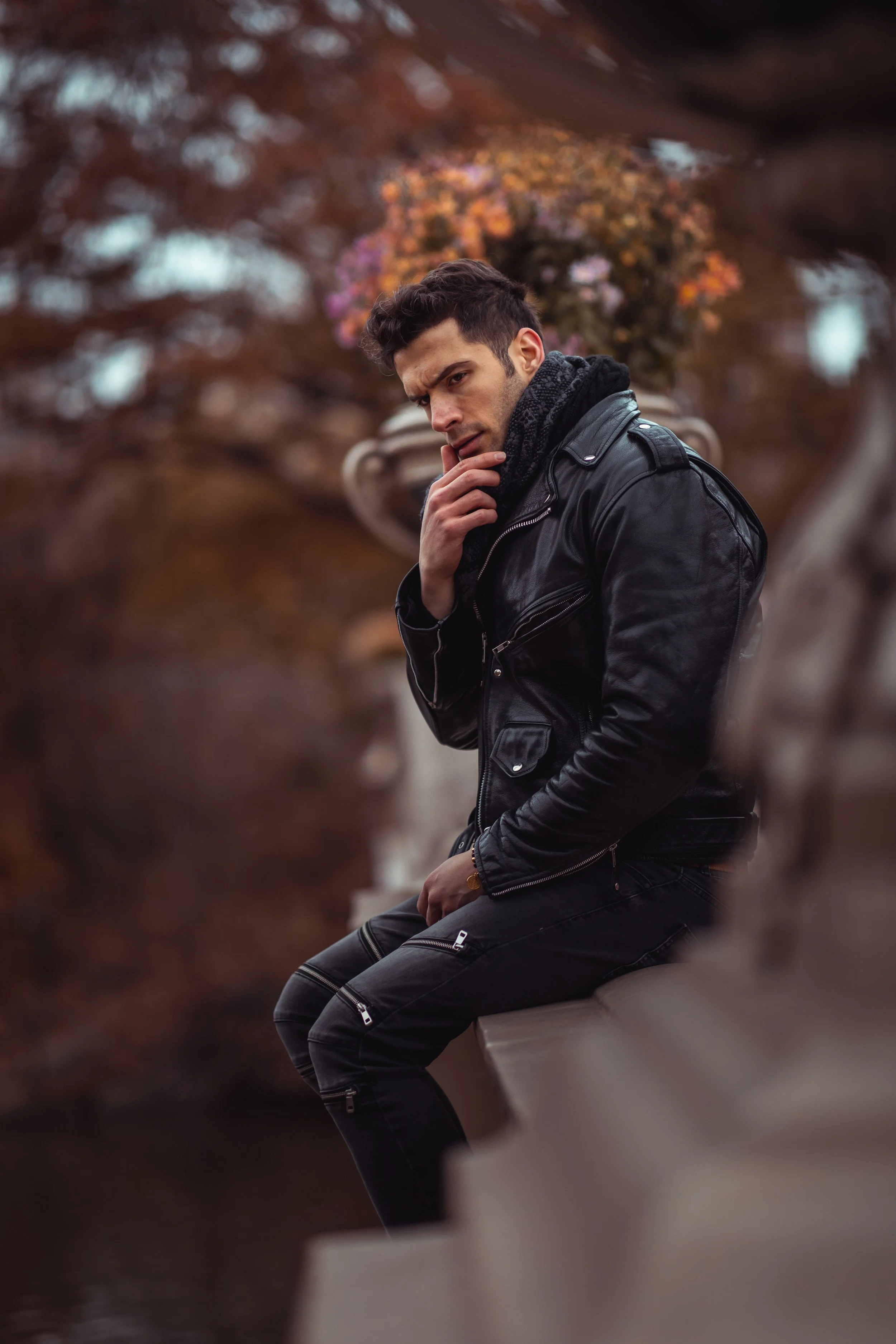 Full-body portrait sitting on Bow Bridge rail in Central Park, NYC.