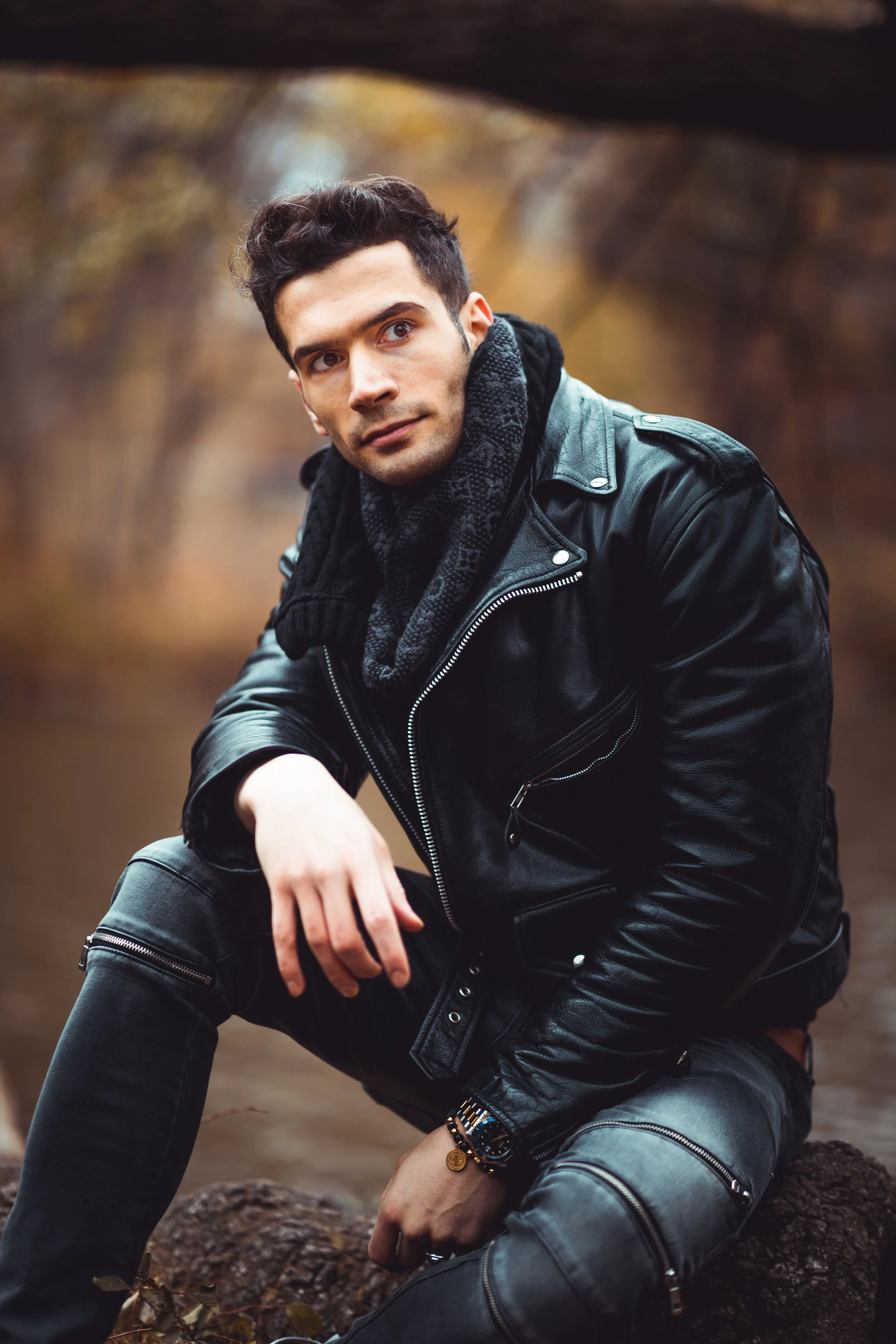 Portrait seated on rocks in Central Park with tree overhead.