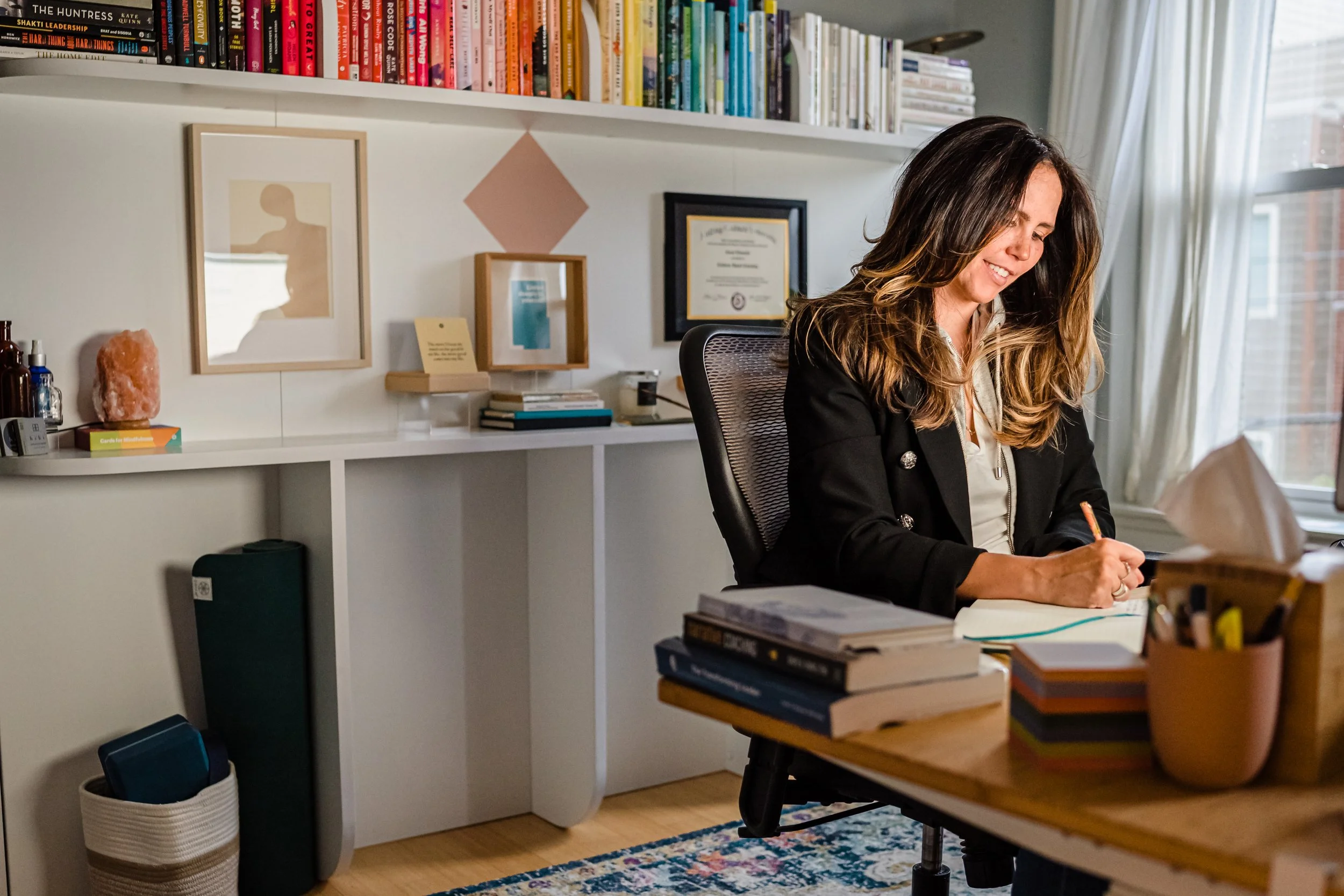 Coral Edwards, ICF-certified coach, writing in a notebook at her desk