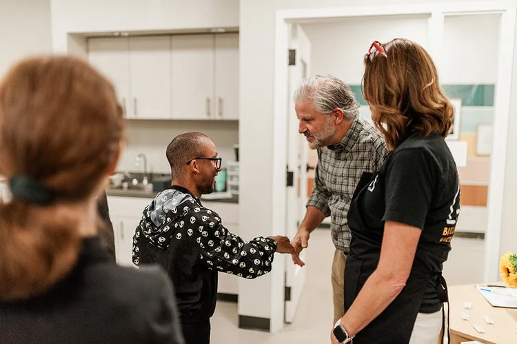 a Citizen shaking hands with a friend in the 210 workshop