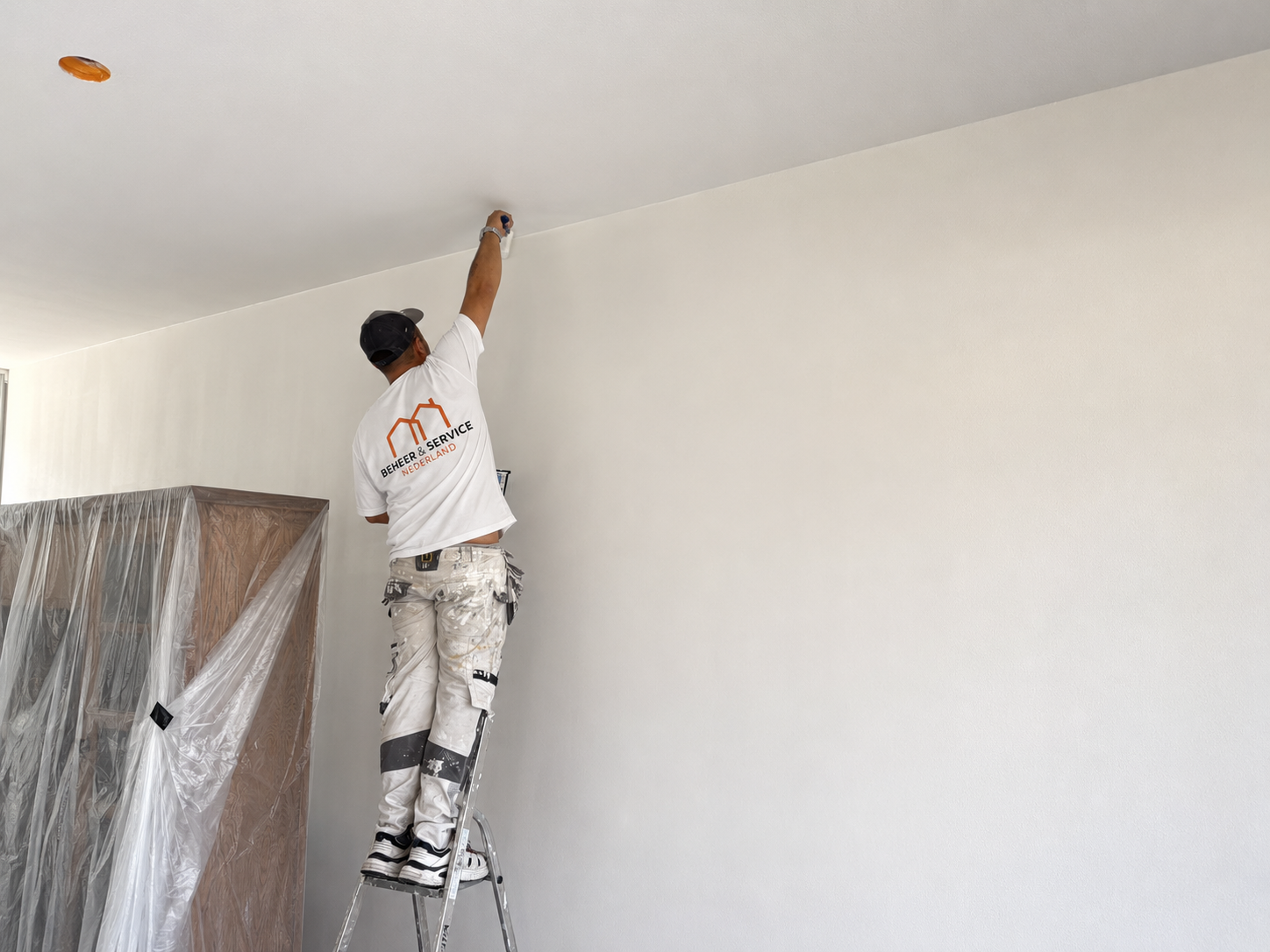 Schilder werkt binnenshuis aan een wand in een woning in Amstelveen