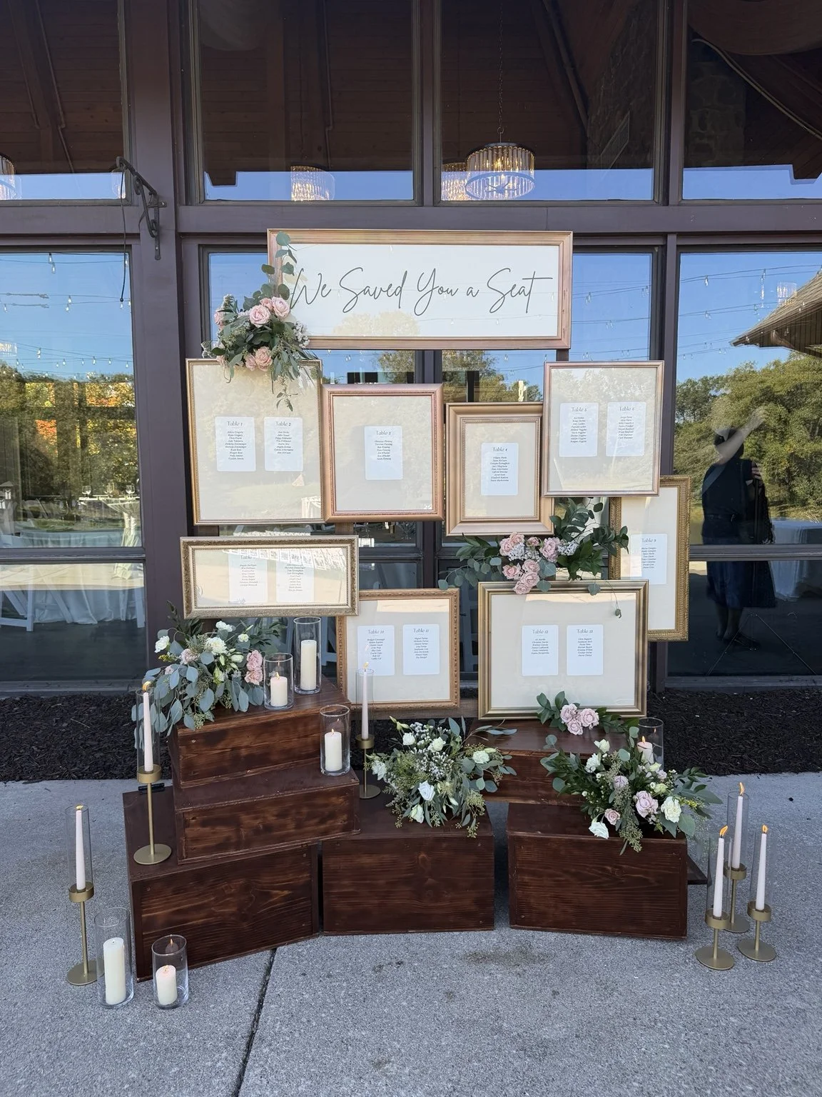 Natalie and Daniel’s seating chart with gold frames, flowers, wood risers, and candles.