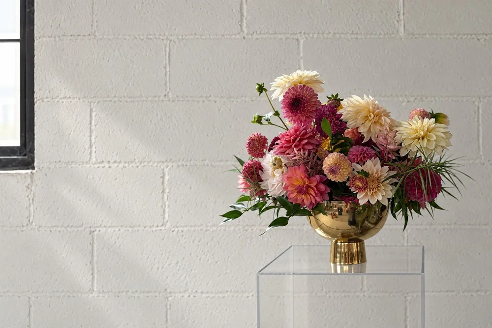 Pink, burgundy and cream dahlias in a brass bowl, designed by Esotarium.