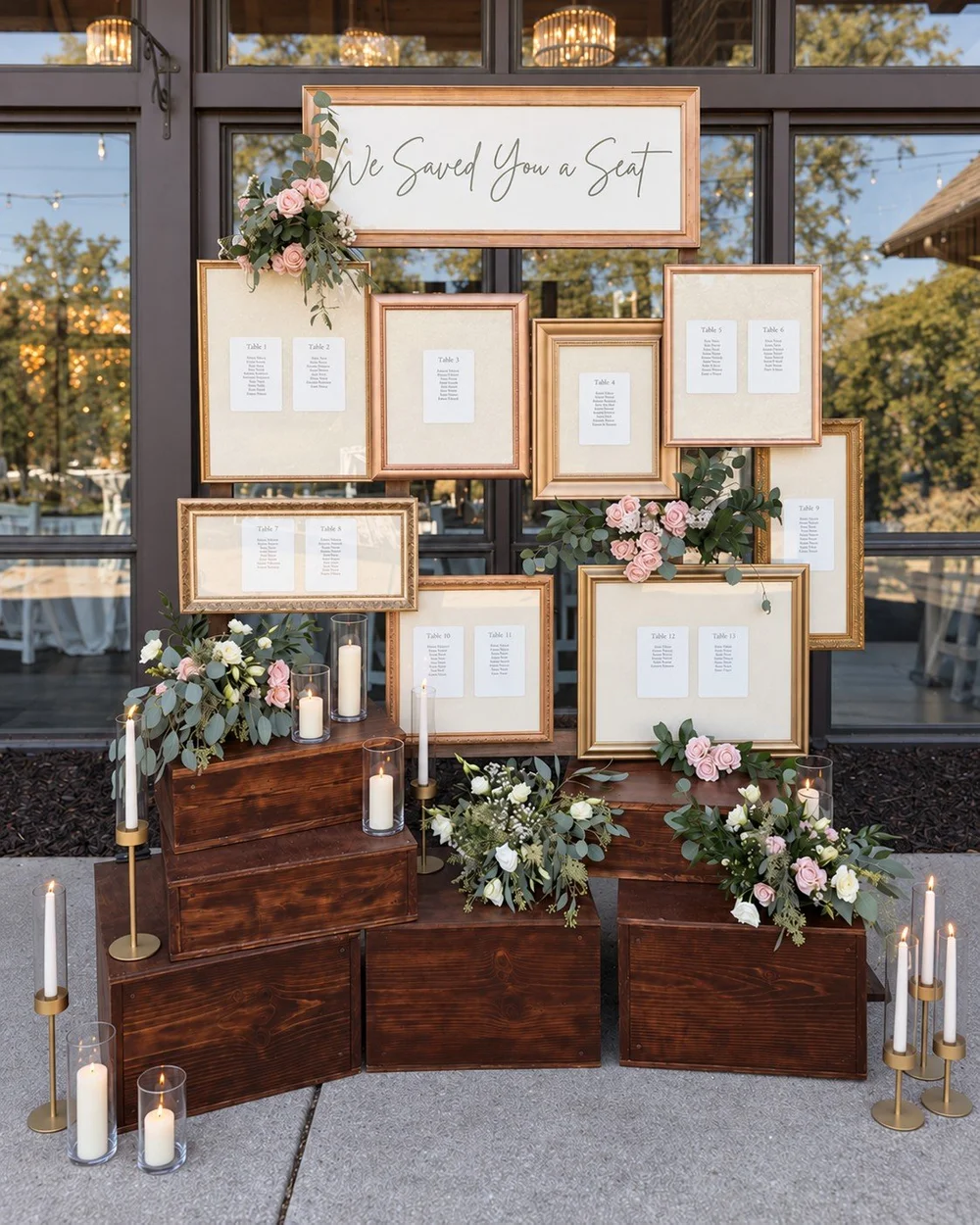 Gold frames, flowers and candles arranged into a wedding seating display.