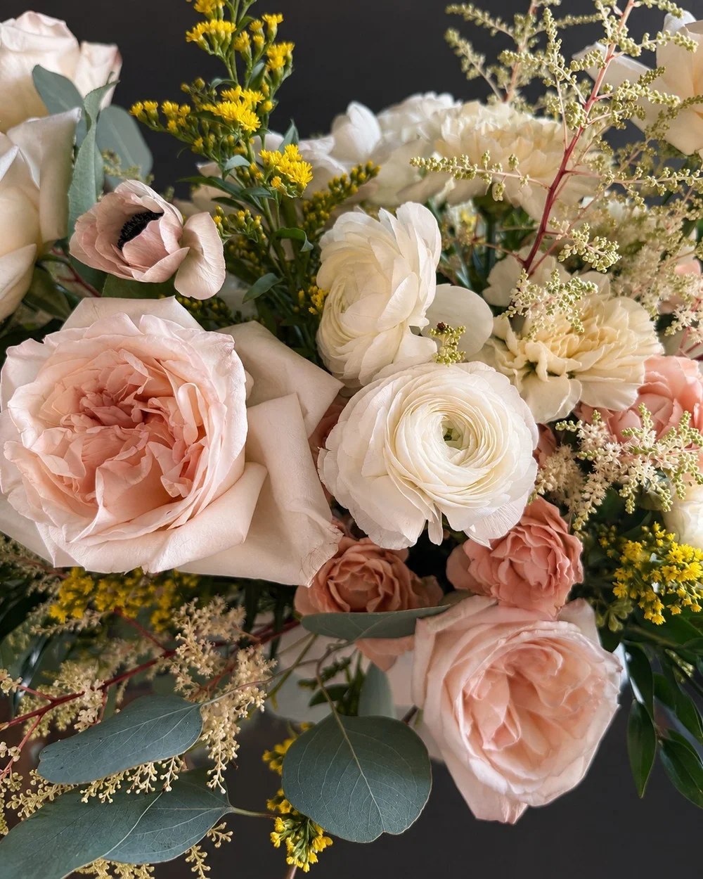 Cream ranunculus, blush roses and eucalyptus in an Esotarium bridal bouquet.