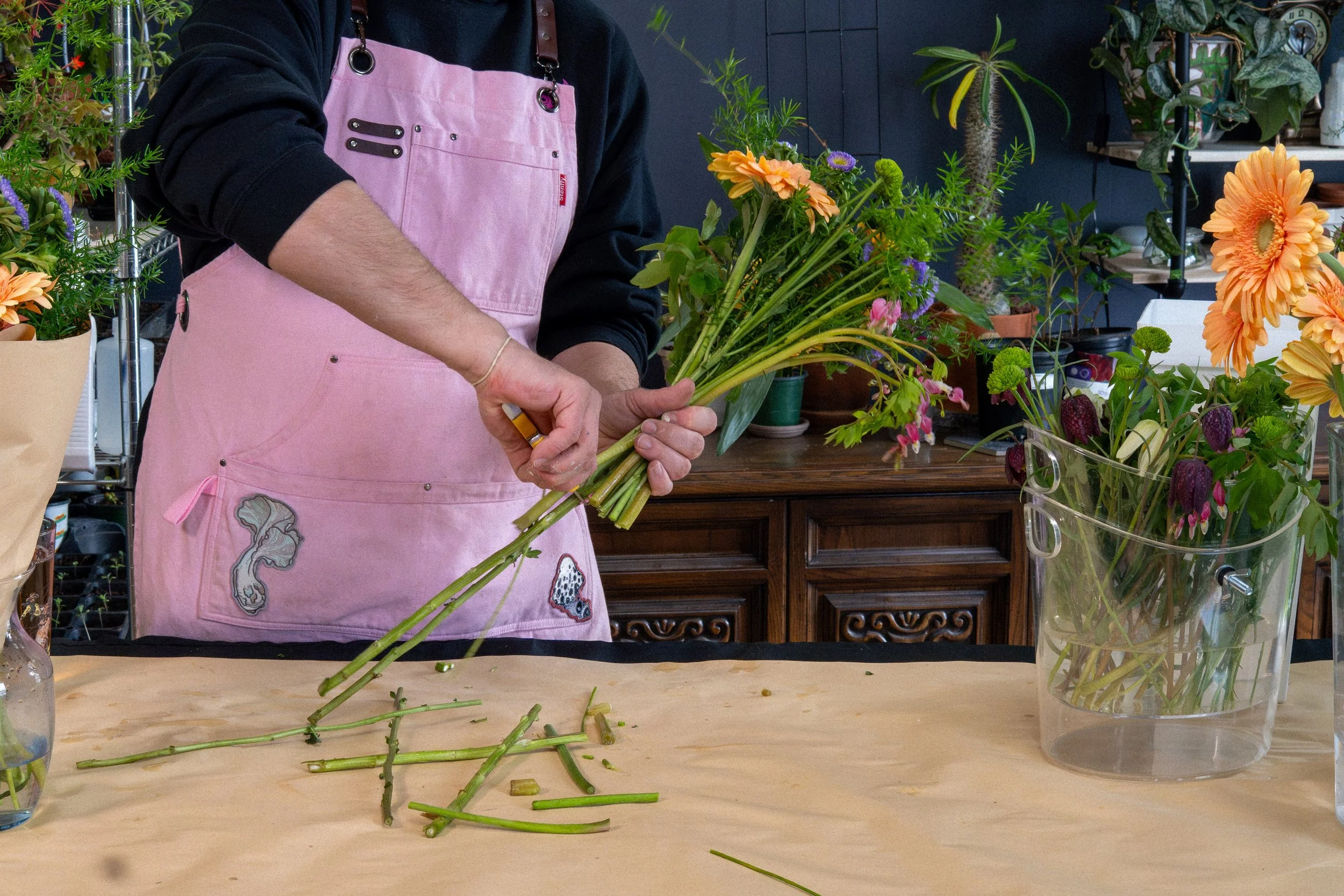 Hands arranging stems at the Esotarium worktable.