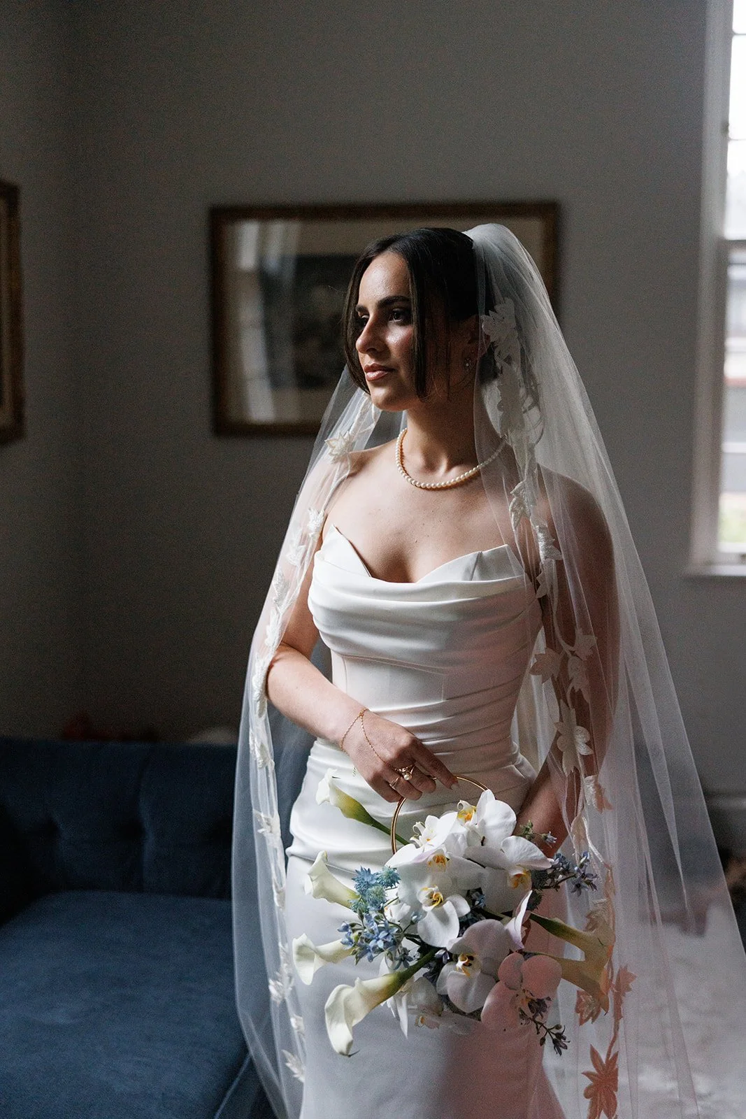 Rachel in her wedding dress and veil, carrying her orchid floral purse.