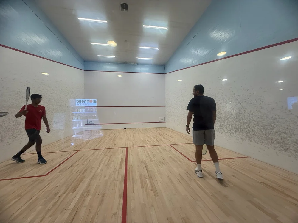 Karim Abdel Gawad sharing a court with a Monmouth junior player