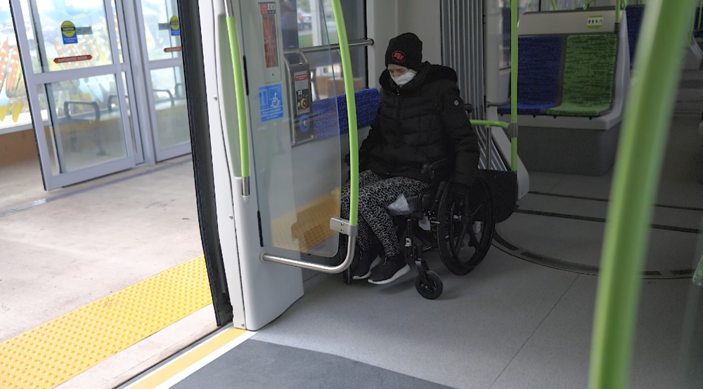 A rider using a wheelchair boards a Valley Line Southeast LRT vehicle through its wide doors at platform level