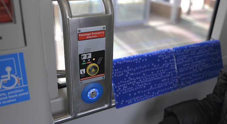 Passenger emergency intercom panel and wheelchair symbol decal beside a row of seats