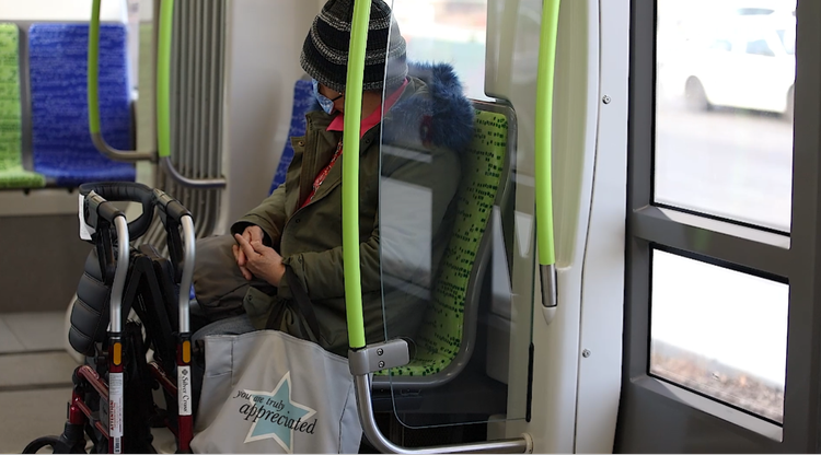 A rider seated on board with a mobility aid beside the seat