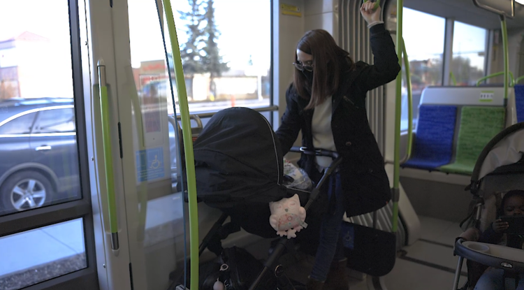 A rider with a stroller stands in the open floor area near the doors