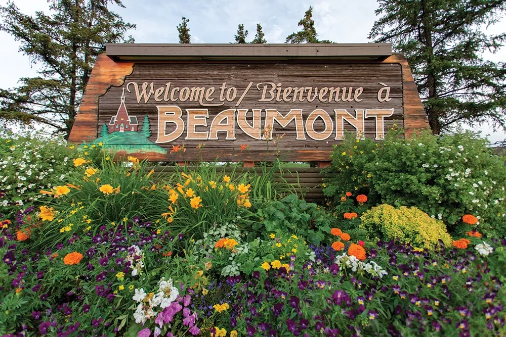 Bilingual Welcome to Bienvenue a Beaumont sign surrounded by flower beds