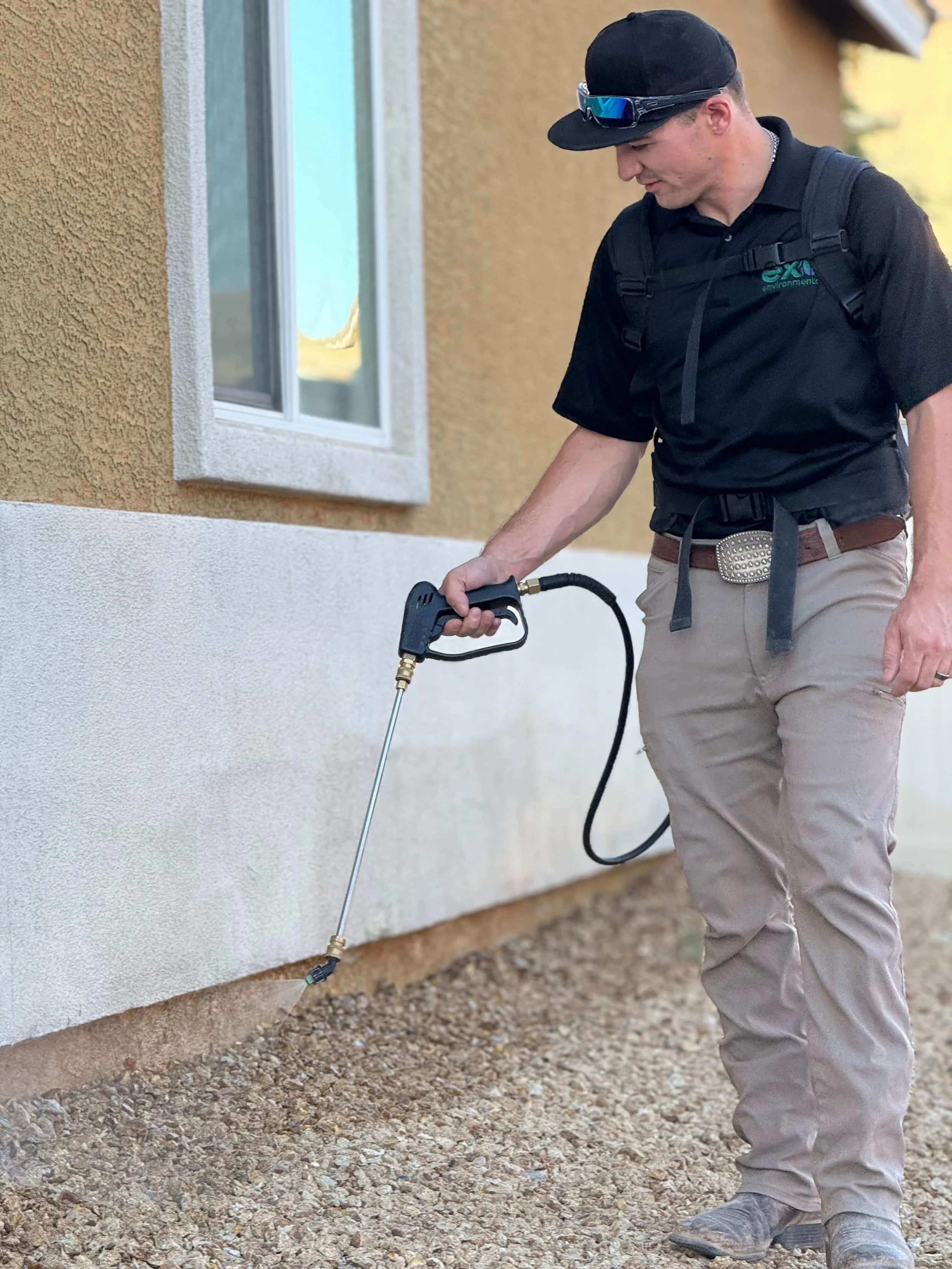Pest control technician spraying home foundation