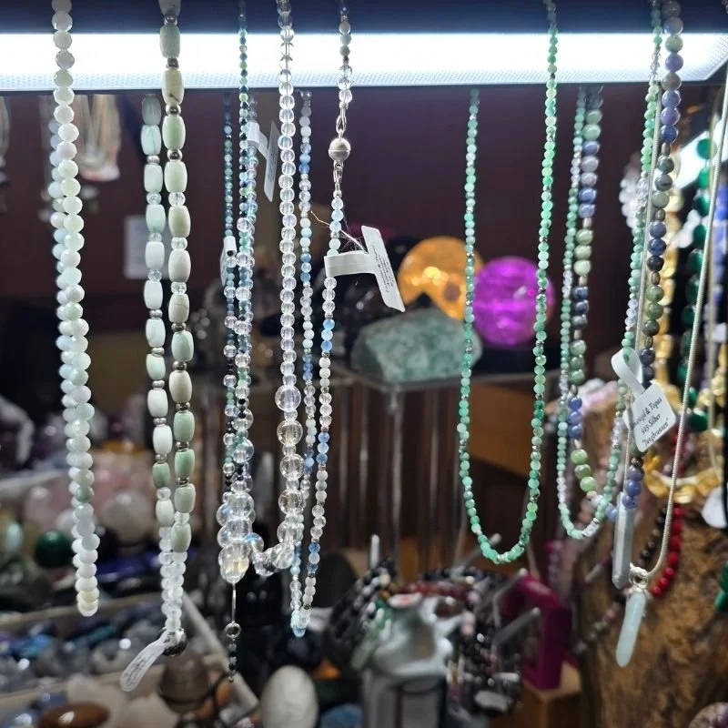 Nahaufnahme der Vitrine mit einer vielfältigen Auswahl an PRANA Edelstein-Armbändern auf der Messe.