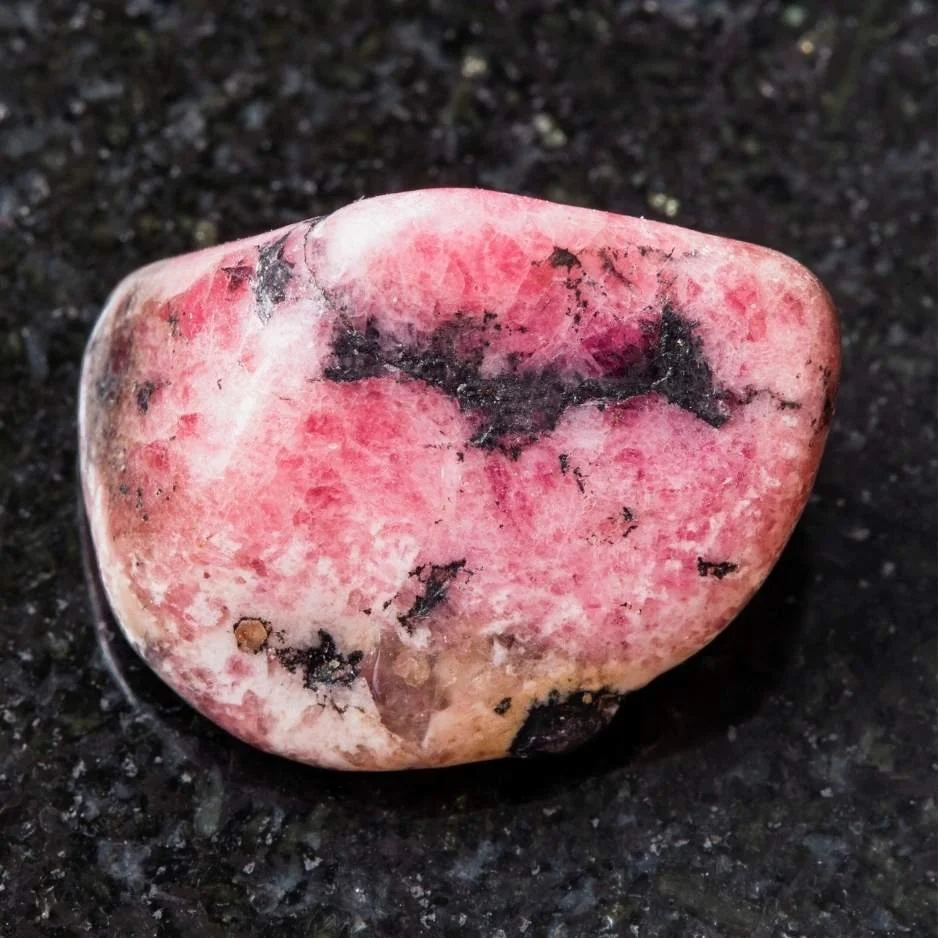 Ein Rhodonit Edelstein mit rosa und schwarzen Flecken, zur Stärkung von Selbstliebe und Vergebung.