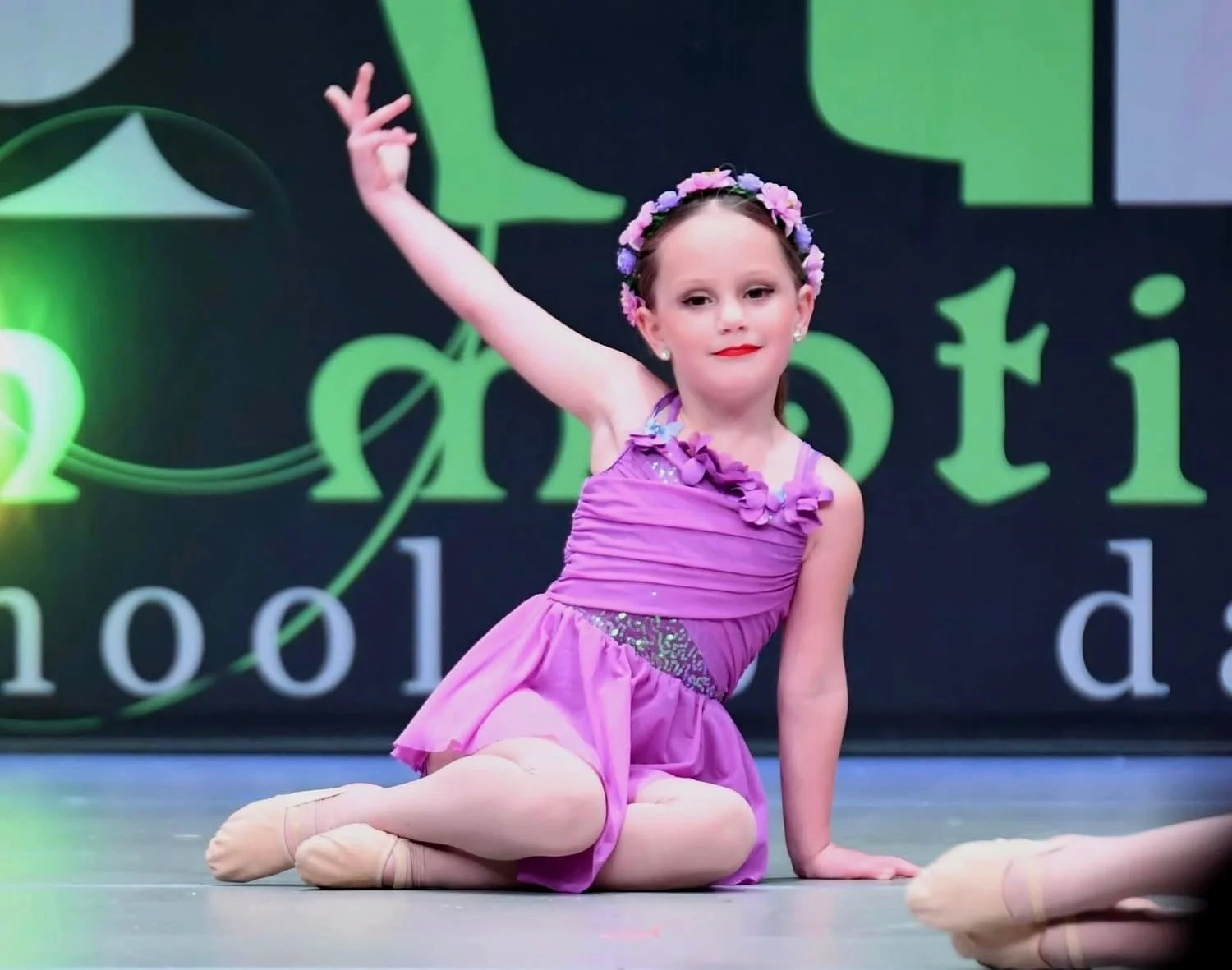 A young AIM dancer performing on stage at a recital