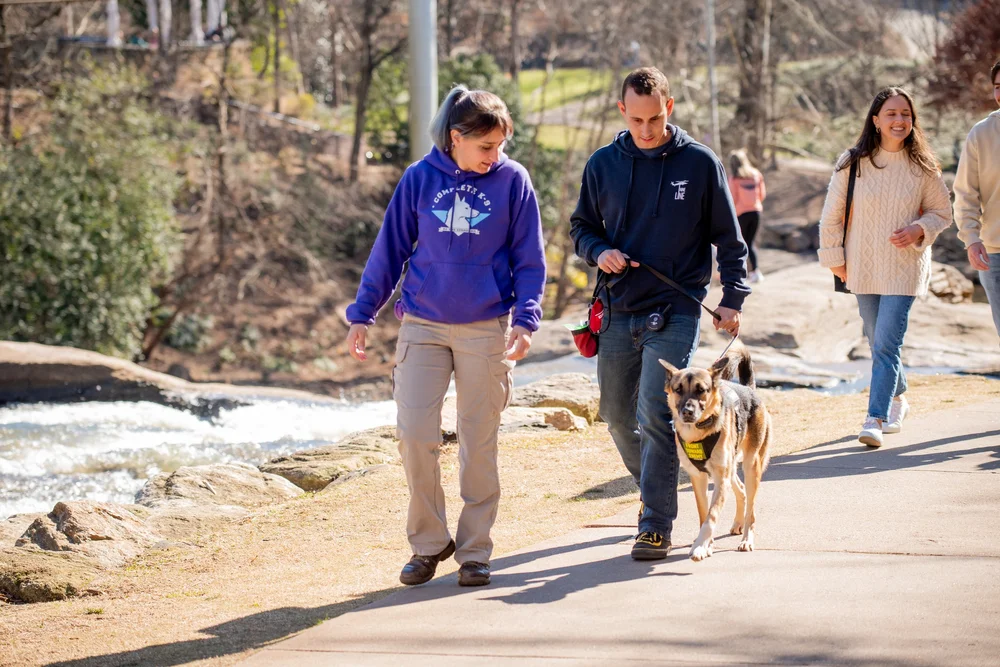 A Complete K-9 trainer coaching an owner on a downtown walk