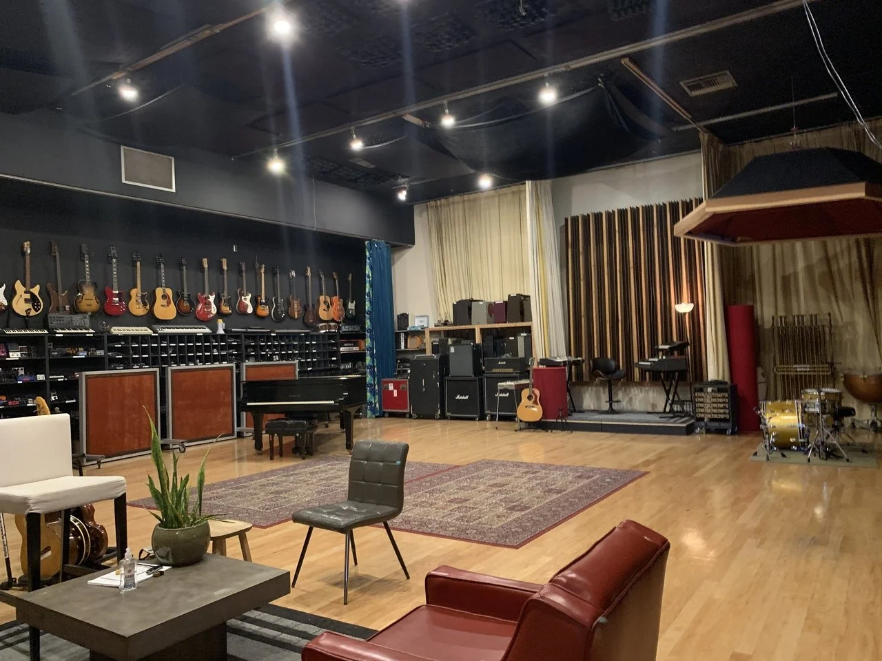 Large Hollywood recording studio live room with instruments, lounge seating and acoustic treatment.