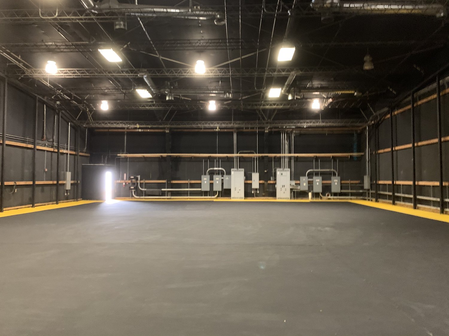 Large black-box film and television soundstage with lighting grid and production power.
