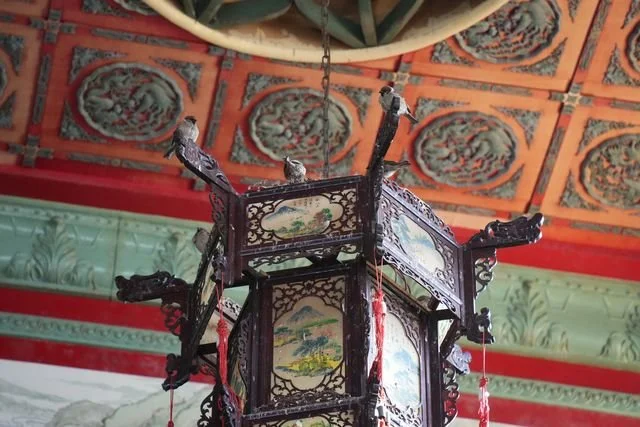 Eurasian tree sparrows (Passer montanus) perch on a painted lantern beneath the temple ceiling.