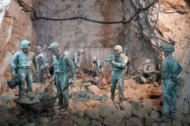 Sculpted tunnel builders stand among tools and broken rock at Beihai Tunnel.