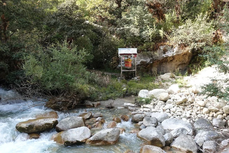A prayer wheel sits above a small channel running through the rocks.