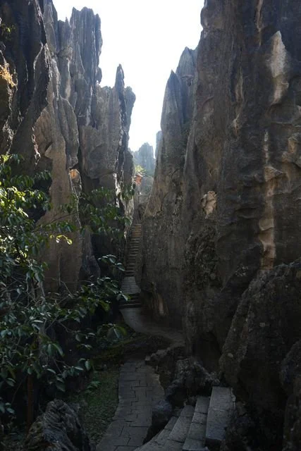 Stone steps wind through a narrow cleft between high rock walls.