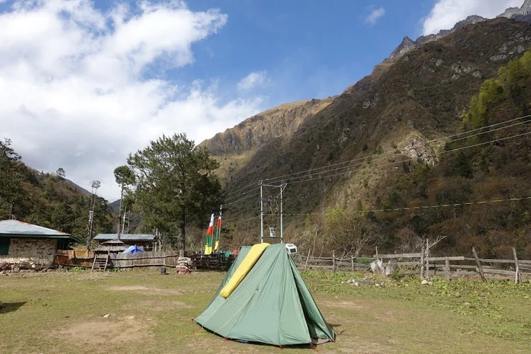 A green tent stands beneath the steep slopes at Thangthangkha.