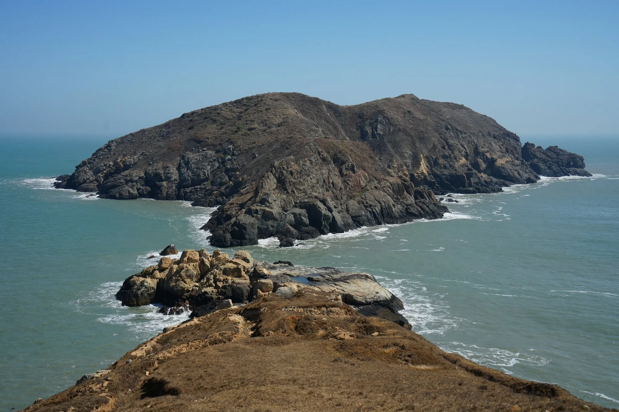 Surf outlines the rocky headlands seen from Daqiu.