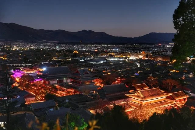 Lights trace Lijiang's roofs and walls below Lion Hill as the sky darkens.