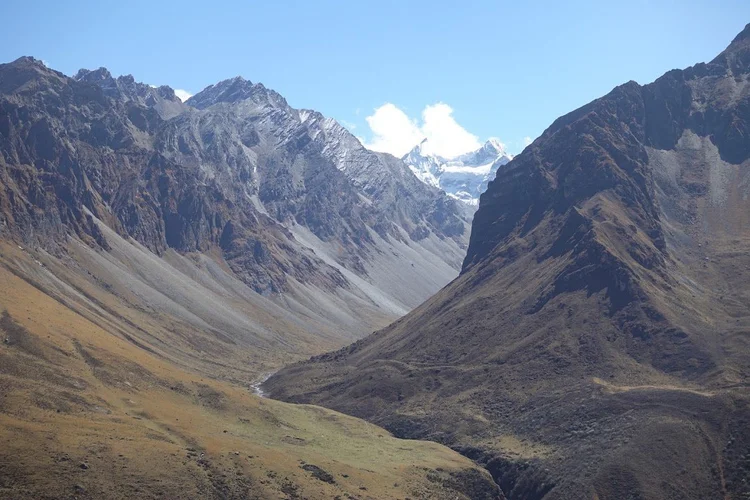A narrow stream winds through the deep valley between bare rock walls.