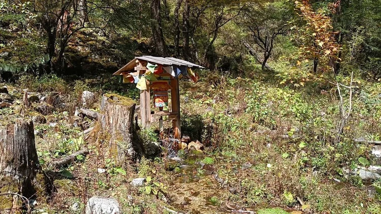 Prayer flags hang from a small shelter above a water-powered prayer wheel.