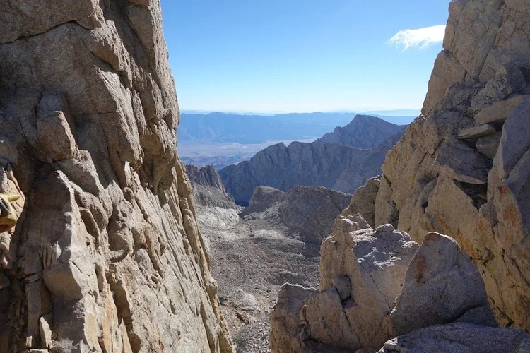 A narrow gap between the granite towers opens a view down the eastern slopes towards the broad valley below.