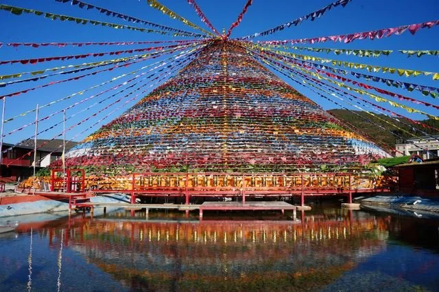 A large canopy of prayer flags is reflected in a pool in Shangri-La.