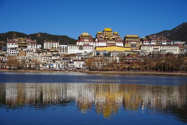 Songzanlin's white walls and golden roofs are reflected in the water below.